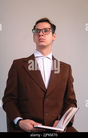 Ein blonder Kaukasusmann, der in einer Jacke gekleidet ist und mit einer Haltung aufschaut, die Selbstvertrauen beweist. Intellektueller Mann auf einem weißen isolierten Hintergrund. Hochwertige Fotos Stockfoto