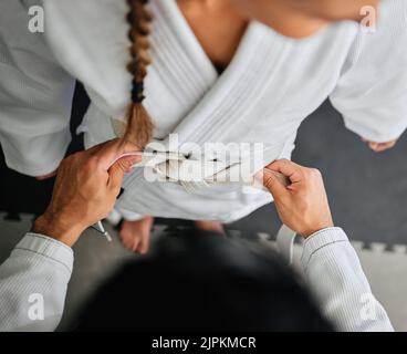 Frau trägt Karate-Gürtel in Fitness-Training-Klasse von Trainer, Dojo-Übung im Fitnessstudio lernen und Training im Sportstudio von oben. Draufsicht Stockfoto