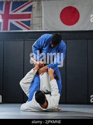 Kampfsportler, Karate- oder Judokämpfer und Athleten, die in einem Wettkampf, Match oder Turnier kämpfen. Japan vs. Großbritannien, Selbstverteidigung und Schutz Stockfoto