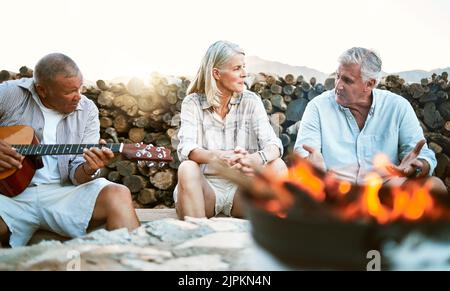 . Senior, Abenteuer und Spaß Wellness Wandern Gruppe von Freunden, entspannen oder eine Pause am Lagerfeuer nach einem Spaziergang auf Outdoor-Bergtour Stockfoto