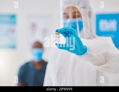 Covid-Impfstoff, -Heilung oder -Behandlung für covid19, gehalten von einem Arzt in einem Krankenhaus. Porträt eines Arztes in einem Schutzanzug mit Gefahrgut Stockfoto