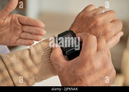 Leitender Mann, der seine Smart Watch mit einer Gesundheitsanwendung ausgestattet hat Stockfoto