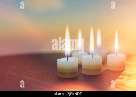 Fünf wachsdicke kurze Kerzen brennen auf einem Holztisch. Religiöses Feiertagsritual, Reinigung, Meditation Stockfoto