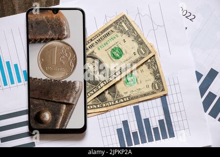 Der Gasschlüssel hält den russischen Rubel als Hintergrund im Telefon und Dollar liegen in der Nähe, der Zusammenbruch des Rubels, Sanktionen gegen Russland, die econ Stockfoto