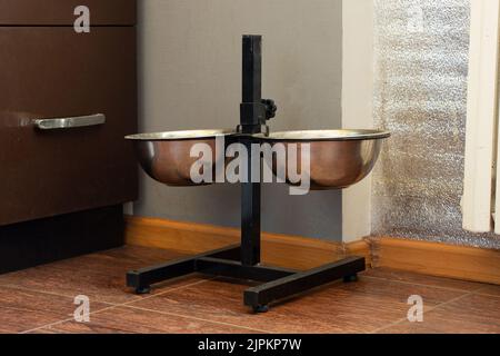Zwei Hundeschüsseln auf einem Ständer auf dem Boden des Hauses in der Wohnung in der Küche, eine Hundekoma-Schale Stockfoto