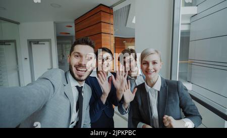 POV von Happy Business Team mit Online-Video-Chat mit Smartphone-Kamera und im Gespräch mit ihren Kollegen in modernen Büros in Innenräumen Stockfoto