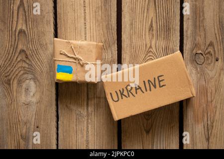 Zwei Kisten mit dem Text Ukraine und der Flagge der Ukraine auf einem Holztisch, humanitäre Fracht für die Ukraine, Krieg, helfen Menschen vom Krieg betroffen 2022 Stockfoto