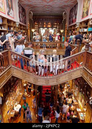 Interieur des schönen Livraria Lello aka Lello Buchhandlung in Porto, Portugal. Der Laden ist voll und die Leute steigen die berühmte rote Treppe hinunter. Stockfoto