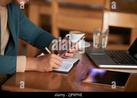 Hände von Menschen, die Nachrichten auf dem Smartphone abrufen und Notizen machen Stockfoto