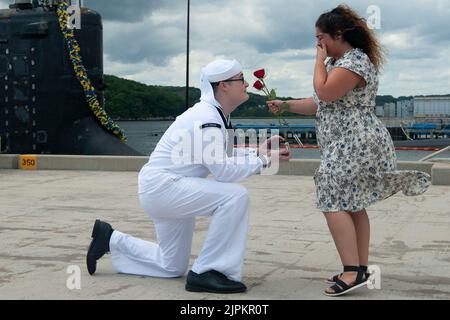 10. August 2022 - Submarine Base New London, Connecticut, USA - Petty Officer 2. Klasse Andrew Frable schlägt seiner Freundin Nevada Currier während einer Heimkehr-Veranstaltung für die USS Indiana (SSN 789) auf der Naval Submarine Base New London in Groton, Connecticut, USA, vor. 10. Indiana kehrte nach seinem vollständigen Einsatz seit der Inbetriebnahme im Jahr 2. in den Heimathafen zurück, um die maritime Strategie der Marine - die nationalen Sicherheitsinteressen und die maritimen Sicherheitsoperationen - im Einsatzgebiet der Flotte von 6. zu unterstützen. Das Schnellangriffs-U-Boot USS Indiana der Virginia-Klasse und die Besatzung operieren unter dem Submarine Squadron (SUBRO) Stockfoto