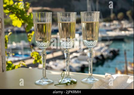 Drei Gläser französischer Champagner Sekt und Blick auf bunte Fischerboote im alten Hafen von Cassis, Provence, Frankreich, Sommerfest in PR Stockfoto