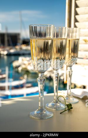 Drei Gläser französischer Champagner Sekt und Blick auf bunte Fischerboote im alten Hafen von Cassis, Provence, Frankreich, Sommerfest in PR Stockfoto