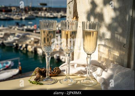 Drei Gläser französischer Champagner Sekt und Blick auf bunte Fischerboote im alten Hafen von Cassis, Provence, Frankreich, Sommerfest in PR Stockfoto