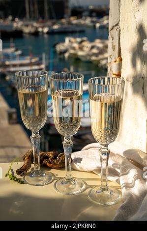 Drei Gläser französischer Champagner Sekt und Blick auf bunte Fischerboote im alten Hafen von Cassis, Provence, Frankreich, Sommerfest in PR Stockfoto