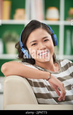 Porträt einer glücklichen attraktiven asiatischen Frau, die Musik hört Stockfoto