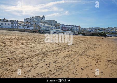 Fußabdrücke und Fußabdrücke an einem ruhigen Porthmeor Beach in St. Ives, in der Nebensaison im März. Fischerhafen von St. Ives in Cornwall. Beliebt bei der Kunst Stockfoto