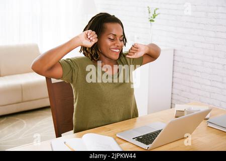 Lächelnder Freiberufler, der sich nach einem langen Arbeitstag ausdehnt Stockfoto