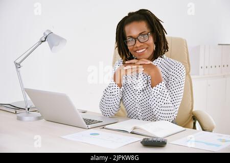Ziemlich lächelnde Geschäftsfrau an ihrem Bürotisch Stockfoto