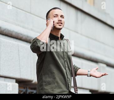 Verlorener Mann, Reisender oder Tourist, der bei einem Telefongespräch nach dem Weg in eine neue Stadt fragt. Ein verwirrter junger Mann im Urlaub in einer Stadt suchen Stockfoto