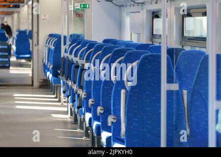 Innenraum des modernen Hochgeschwindigkeits-Expresszuges für Passagiere, Reihe leerer, weicher Sitze aus blauem Stoff. Stockfoto