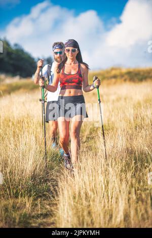 Junges Paar bei einer Nordic-Walking-Wanderung auf einem Bergwanderweg Stockfoto