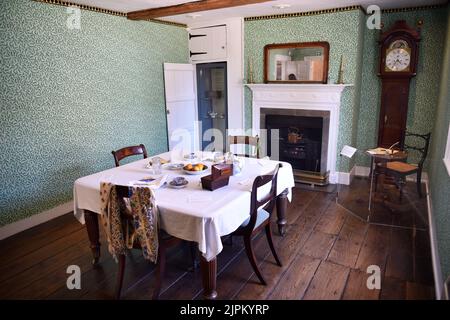 Esszimmer mit Jane Austens Schreibtisch unter der Uhr, Jane Austens Haus, Chawton, in der Nähe von Alton, Hampshire, VEREINIGTES KÖNIGREICH. Stockfoto