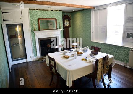 Esszimmer mit Jane Austens Schreibtisch unter der Uhr, Jane Austens Haus, Chawton, in der Nähe von Alton, Hampshire, VEREINIGTES KÖNIGREICH. Stockfoto