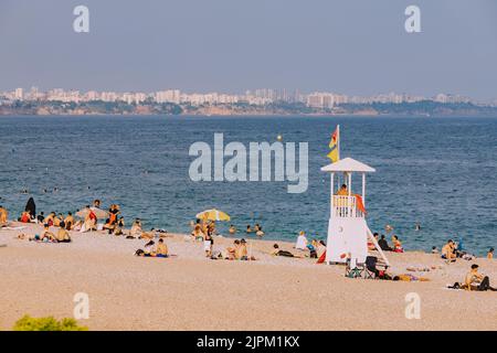 10. Juli 2022, Antalya, Türkei: Konyaalti Strand mit Liegestühlen und Rettungsturm und Urlauber schwimmen und chillen im erfrischenden Meerwasser Stockfoto