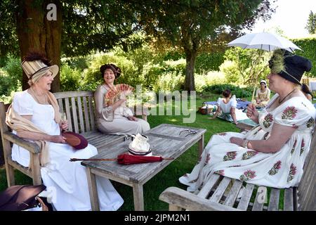 Frauen in Regency-Ära (1811-20) Kostüm sitzen im Garten von Jane Austen’s House, Chawton, in der Nähe von Alton, Hampshire, Großbritannien. Stockfoto