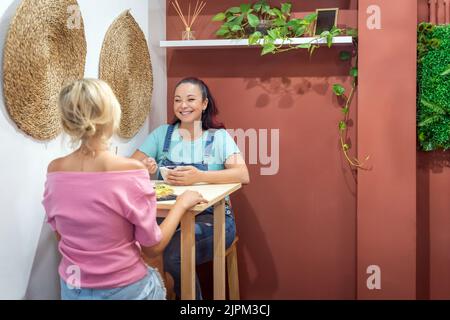 Zwei Freundinnen unterhalten sich beim gemeinsamen Frühstück in einem Café. Freundschafts- und Essenskonzept. Stockfoto