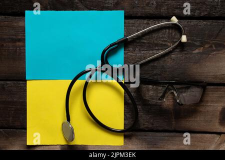 Das Stethoskop liegt auf der Nationalflagge der Ukraine gelb-blau, Kriegsrecht in der Ukraine, medizinische Versorgung im Krieg.Krieg in der Ukraine 2022 Stockfoto