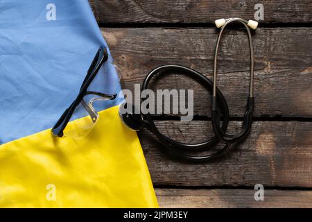 Das Stethoskop liegt auf der Nationalflagge der Ukraine gelb-blau, Kriegsrecht in der Ukraine, medizinische Versorgung im Krieg.Krieg in der Ukraine 2022 Stockfoto