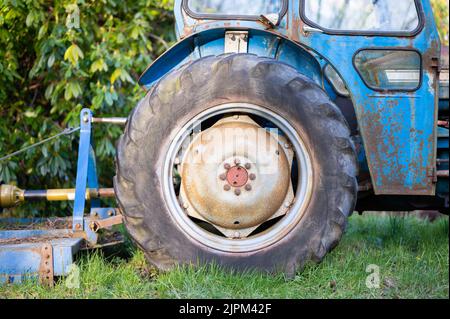 Ein alter blauer Traktor mit seinen großen Rädern auf dem Feld Stockfoto