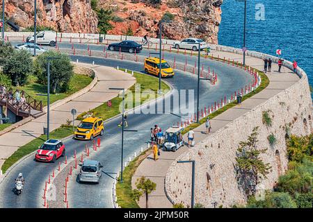 10. Juli 2022, Antalya, Türkei: Autos und Motorräder fahren auf der kurvenreichen Serpentinen-Straße zum wunderschönen Konyaalti-Strand am mittelmeer Stockfoto