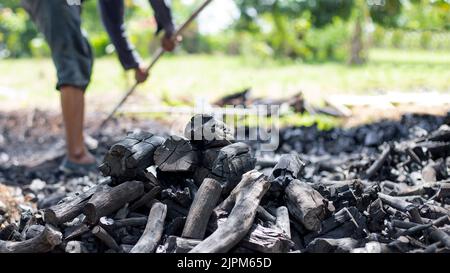 Die Bauern verbrennen Holzkohle aus Holz, das von der Farm abgeschnitten ist. Stockfoto