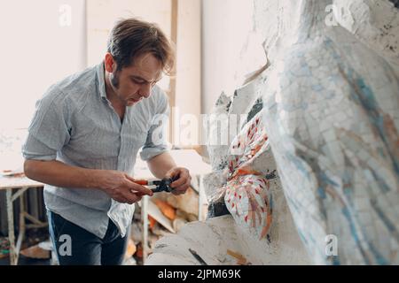 Arbeitsplatz Mosaiken Meister machen Smaltglas Mosaik Panel. Mann Mosaiker bei der Arbeit Stockfoto