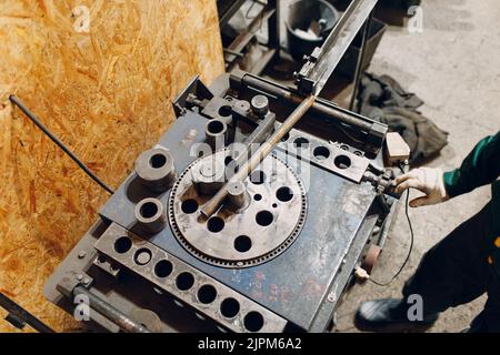 Arbeiter in der Fabrik mit der industriellen Maschine zum Biegen der Metallrohre. Stockfoto