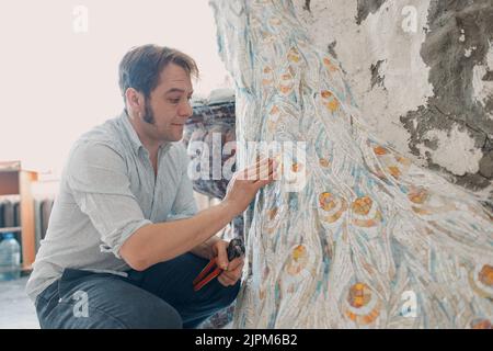 Arbeitsplatz Mosaiken Meister machen Smaltglas Mosaik Panel. Mann Mosaiker bei der Arbeit Stockfoto