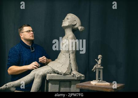 Mann Bildhauer schafft Skulptur Büste Ton menschliche Frau Skulptur. Werkstatt für die Erstellung von Statuen. Kleinunternehmen. Stockfoto