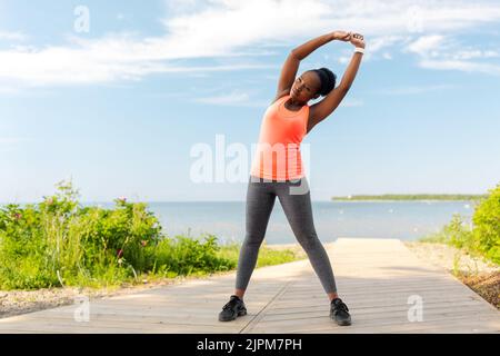 Junge afroamerikanische Frau, die am Strand trainiert Stockfoto