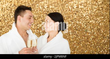 Glückliches Paar in den Bademänteln im Spa, das Champagner trinkt Stockfoto