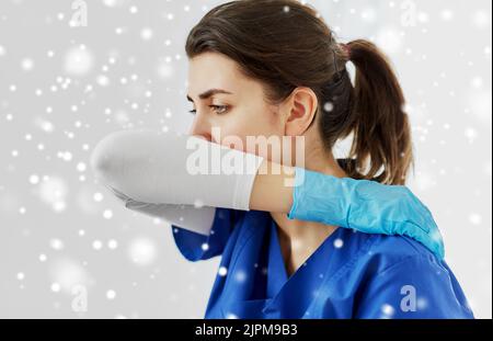 Arzt oder Krankenschwester hustet, wobei der Mund mit dem Ellbogen bedeckt ist Stockfoto