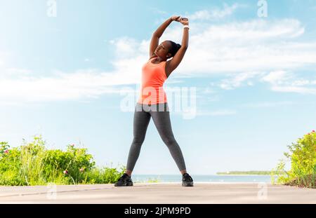 Junge afroamerikanische Frau, die am Strand trainiert Stockfoto