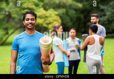 Lächelnder Mann mit Yogamatte über Gruppe von Menschen Stockfoto