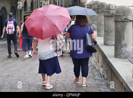 Die Sommerwoche ist von Wetterinstabilität geprägt. Gewitter und leuchtende Zaubersprüche blockieren den riesigen Touristenstrom nicht. Regenschirme offen gefärbt. Stockfoto