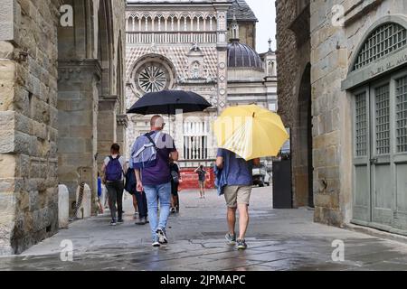 Die Sommerwoche ist von Wetterinstabilität geprägt. Gewitter und leuchtende Zaubersprüche blockieren den riesigen Touristenstrom nicht. Regenschirme offen gefärbt. Stockfoto