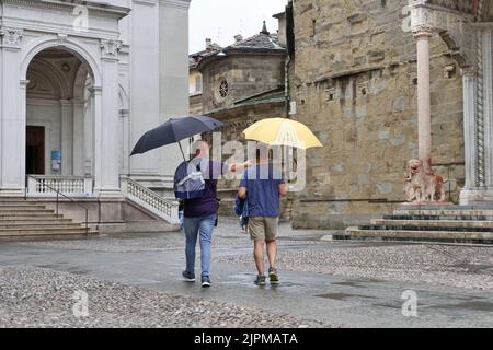 Die Sommerwoche ist von Wetterinstabilität geprägt. Gewitter und leuchtende Zaubersprüche blockieren den riesigen Touristenstrom nicht. Regenschirme offen gefärbt. Stockfoto