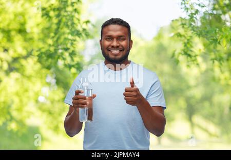 Glücklicher afrikanischer Mann mit Wasser in Glasflasche Stockfoto