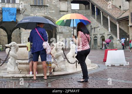 Die Sommerwoche ist von Wetterinstabilität geprägt. Gewitter und leuchtende Zaubersprüche blockieren den riesigen Touristenstrom nicht. Regenschirme offen gefärbt. Stockfoto