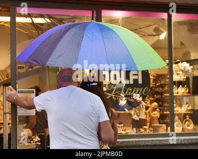 Die Sommerwoche ist von Wetterinstabilität geprägt. Gewitter und leuchtende Zaubersprüche blockieren den riesigen Touristenstrom nicht. Regenschirme offen gefärbt. Stockfoto